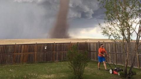 Stunning photo shows a man casually mowing his lawn as tornado looms