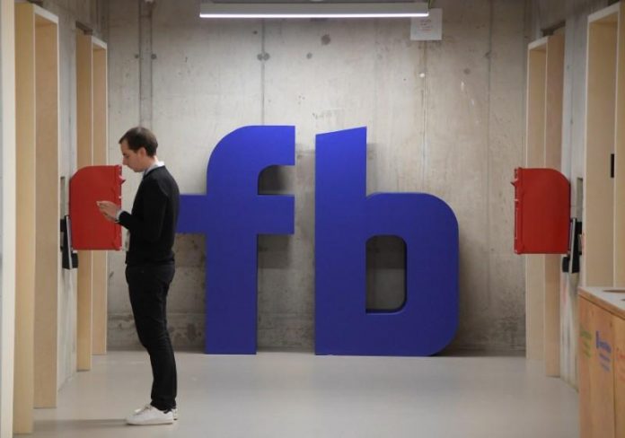 A man waits for an elevator in front of a logo at Facebook's headquarters in London UK may use taxes to get tech giants to do more to fight extremism, minister says